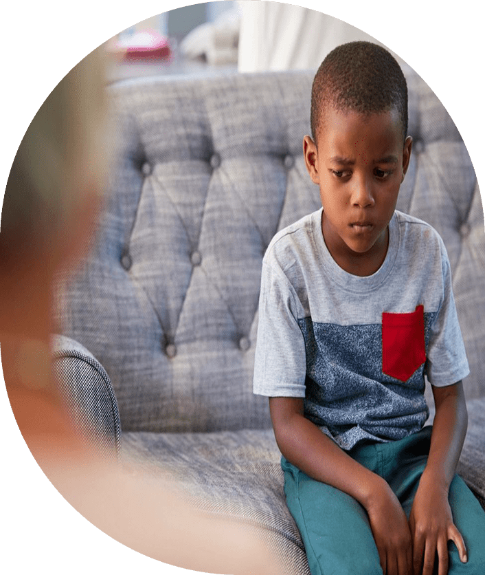 A boy sitting on the couch with his head down.